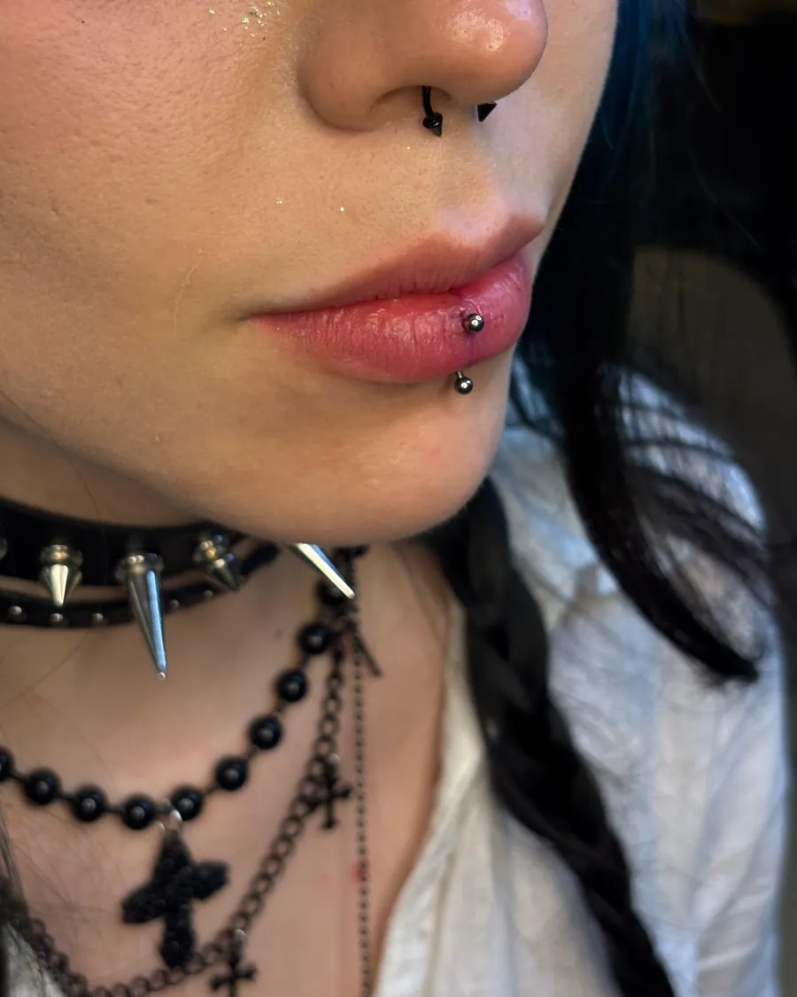 Labret vertical na lateral do lábio inferior, com bolinhas de titânio, e septo com argola preta